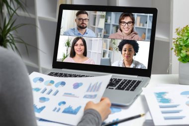 Bilgisayar kullanarak internet üzerinden iş adamlarıyla video konferansı. Bir kadın meslektaşlarıyla uzaktan konuşurken istatistiksel ve mali raporlar tutar.