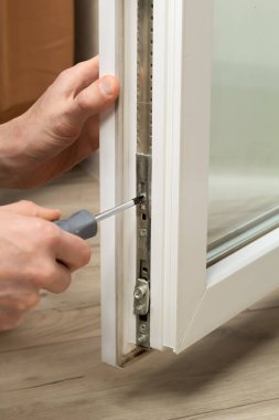 İnşaatçı elinde tornavida tutan plastik bir camla çalışıyor..