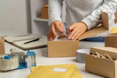 A warehouse worker is busy with the logistics of shipping the item in a box for postage.