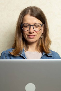 Genç bir kadın evdeki kanepede otururken dizüstü bilgisayarda çalışıyor..