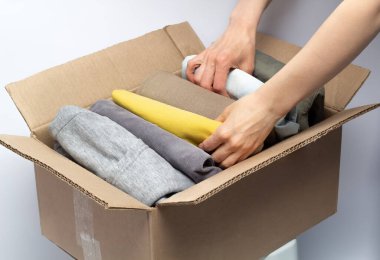 Bir kadının ellerinde bağışlamak için giysi dolu bir kutu. Hayırseverlik konsepti. Atık geri dönüşümü.