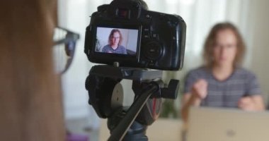 Shooting a video of a young man on a professional vlog camera.
