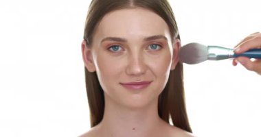 Makyöz, fırça kullanmadan önce genç ve güzel bir kadına yüz makyajı yapar..