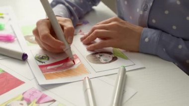 Hands of an artist drawing anime characters on paper. Illustrated storyboard on paper.