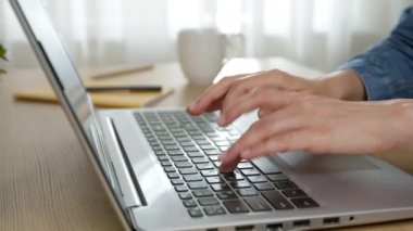 Hands of a business woman typing on a laptop keyboard while working in the office.