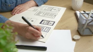 UI designer sketches the user interface of a web application for a mobile phone. A UX developer creates a prototype for a smartphone.