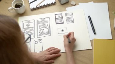 UI designer sketches the user interface of a web application for a mobile phone. A UX developer creates a prototype for a smartphone.