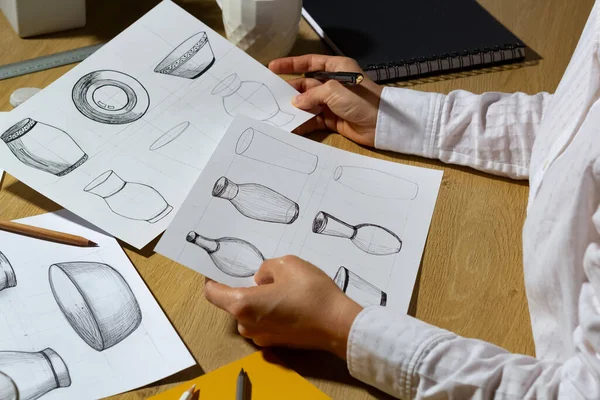 The designer draws sketches of dishes on paper. The artist creates kitchen utensils for production.