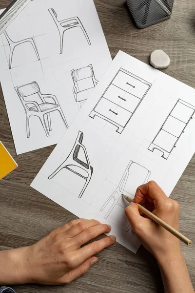 Hands of an artist sketching furniture. Creation of design of chairs and cabinets for the interior.