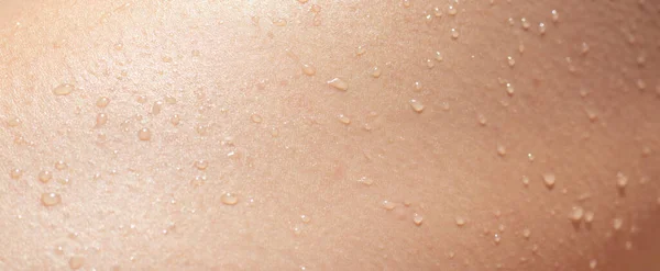 Textura da pele feminina molhada com gotas líquidas close-up. corpo humano bronzeado com gotas de água. Imagem De Stock