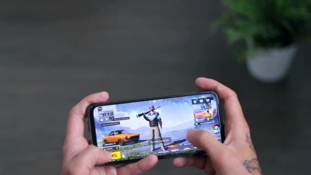 Cyprus Protoras 18 oktober 2021 jongen houdt smartphone en het spelen van PUBG mobiele online game, beroemde online actie spel. online games op een smartphone. — Stockvideo