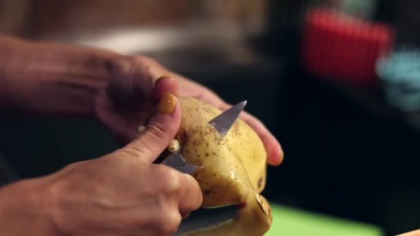 Menina com uma faca descasca batatas close-up. limpeza de vegetais e culturas de raiz. Cozinha caseira. A mãe é dona de casa. cozinhar em casa. — Vídeo de Stock