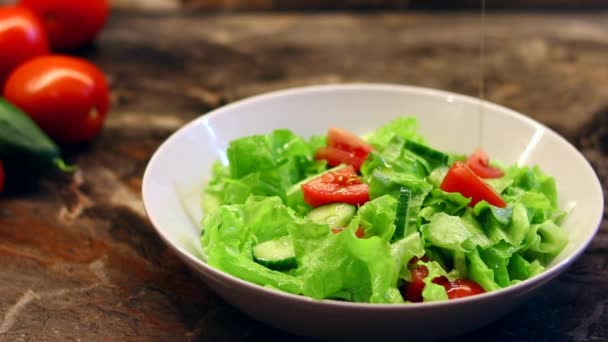 Hospodyně nalévá olivový olej na čerstvý zeleninový salát s listy salátu na talíři. Vaření lahodný salát rajčat, okurka se salátem v kuchyni doma. Zdravé chutné jídlo doma — Stock video