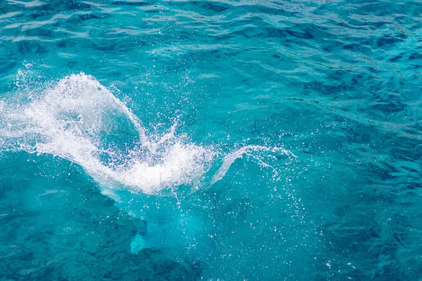 Розщеплення блакитної, морської води з піни бульбашками. Сплеск природи в літній день. синій морський фон з бризкою води. концепція морських відпусток . Стокове Фото