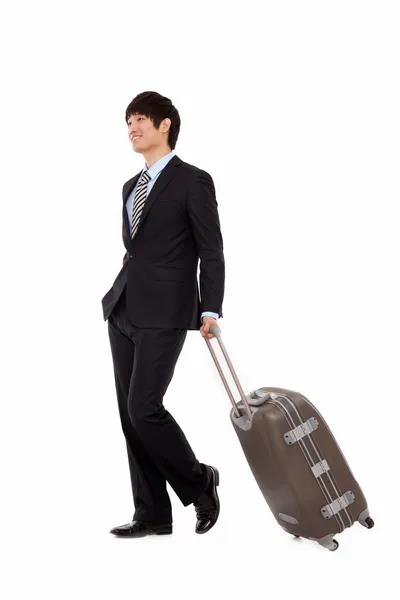 Businessman walking along pulling some travel luggage — Stock Photo, Image