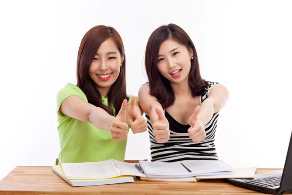 Молодые азиатские студентки с большим пальцем на столе — стоковое фото