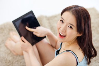 Genç Asyalı kadın evde pad pc kullanarak.