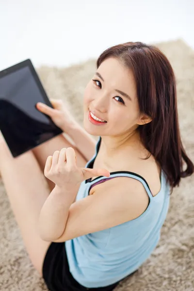 Asiatique femme à l'aide d'un pad PC sur le sol et montrer pouce . — Photo