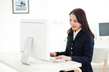 bilgisayar kullanan mutlu Asyalı genç kadın.