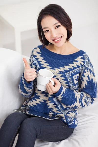 Young Asian woman using a pad PC and showing thumb.