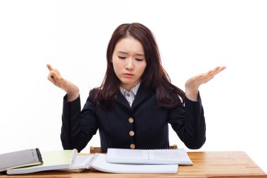 Genç Asyalı öğrenci masada zorlanıyor.