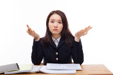 Genç Asyalı öğrenci masada zorlanıyor.