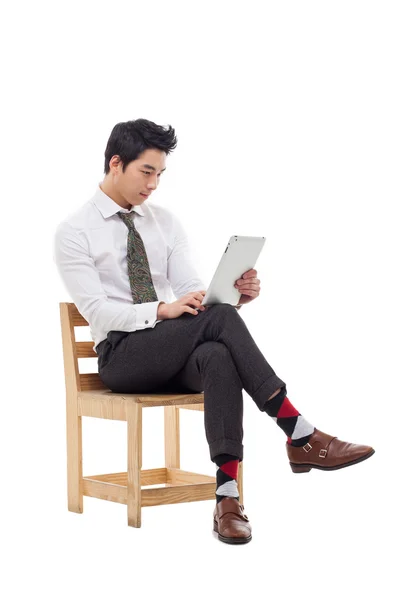 Joven asiático hombre de negocios usando una almohadilla PC sentado en la silla . — Foto de Stock