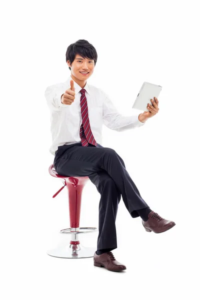 Молодой азиатский бизнесмен с помощью планшетного ПК сидит на стуле . — стоковое фото