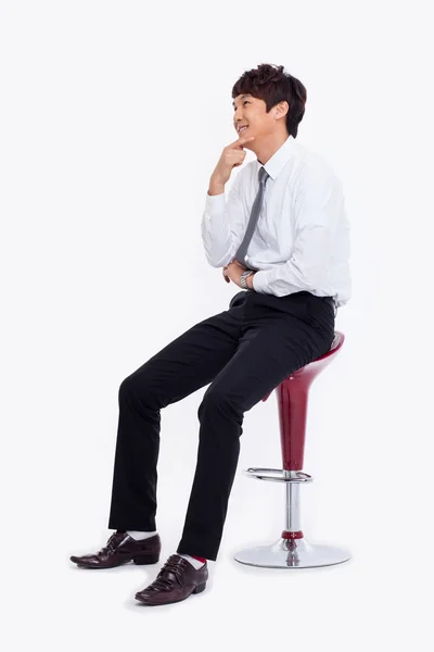 Молодой азиатский бизнесмен сидит на стуле — стоковое фото
