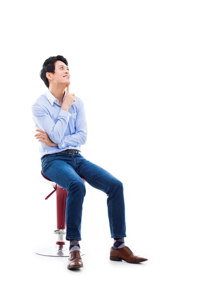 Asijský mladík myslí na židli. — Stock fotografie