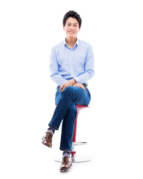 Fiatal ázsiai ember ül a széken. Jogdíjmentes Stock Képek