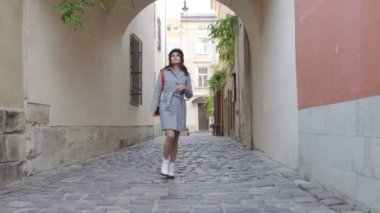 Genç ve güzel bir kız eski kasabada yürüyor ve mimariyi inceliyor. Dişlerinde diş teli olan genç bir kadın.