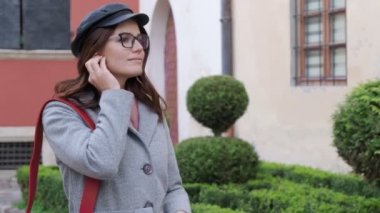 Gözlüklü genç bir kız kablosuz kulaklık takar ve akıllı bir telefondan müzik açar. Diş teli takan genç bir kadın mutlu bir şekilde gülümser ve müziğe yönelir.