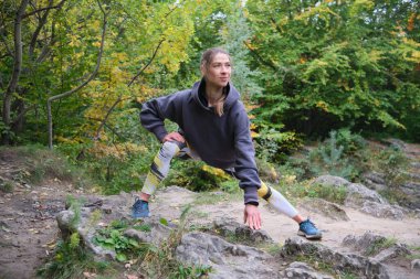 Genç bayan sonbahar parkında kayaların arasında spor yapıyor. Kız spor için doğaya gider. Sağlıklı Yaşam Tarzı. 