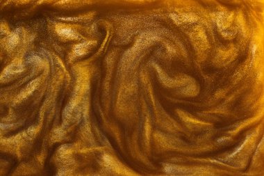 Sıvı altının dokusu ve parlak pigmentler. Dalgaların soyut altın dokusu, girdaplar. Altın likit akrilik boya. Modern tasarım ögesi. 