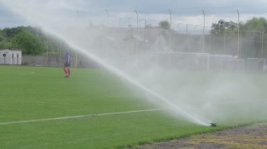 Lawn irrigation system. Watering the football field before the match. Care of the grass on the football field.