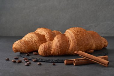 Karanlık taş bir masada tarçınlı kruvasan. Fransız kahvaltısı. Reklam için kompozisyon ve kafe ve restoran menüleri