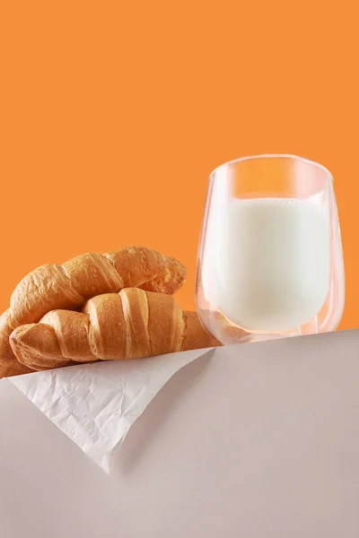 Delicious croissants and a glass of milk on a yellow background. Advertising concept.