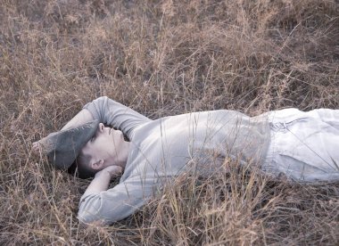 Kuru çimenlerde yatan 18 yaşında bir gencin portresi..