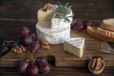 Beyaz küflü peynir, tahta kesme tahtasındaki fındık ve üzümler. Gıda arkaplanı.