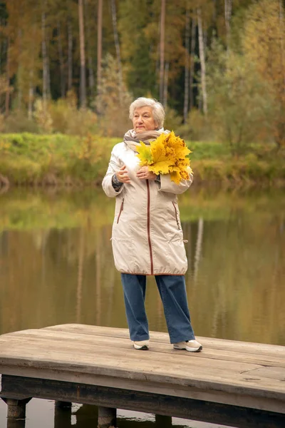 Eine Ältere Frau Mit Einem Strauß Gelber Ahornblätter Steht Einer — Stockfoto