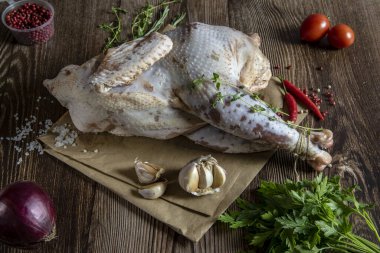 Taze çiğ et. Baharatları ve baharatları olan solgun bir tavuk leşi pişirmeye hazır, yemek kağıdının üzerinde yatıyor..