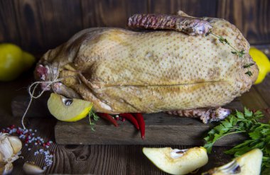 Taze çiğ et. Ot, baharat ve ayva dilimli ördek leşi ahşap bir kesim tahtasının üzerinde yatıyor..