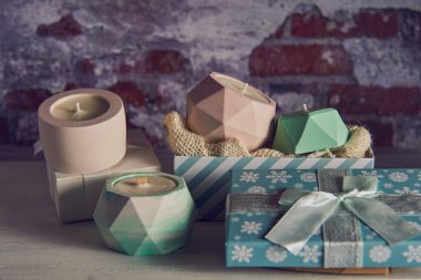Renkli el yapımı soya mumları seramik şamdanların içinde tuğla duvar arkasındaki bir Noel hediye kutusunda..