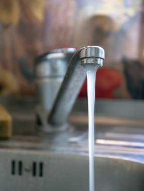 Mutfak lavabosunun üstündeki musluk. Musluğun önüne odaklan..