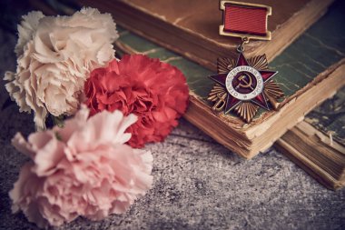 Zafer Günü 9 Mayıs bayram arkaplan kompozisyonu, Rusça metnin İngilizce 'ye çevrildiği Sovyet düzeni Vatanseverlik Savaşı, İkinci Dünya Savaşı, kitaplar, karanfil çiçekleri, seçici odaklanma, tonlama
