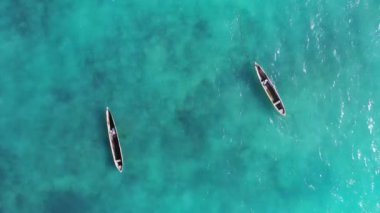 Zanzibar. Tanzanya 'da. Turkuaz Hint okyanus dalgaları üzerinde yüzen balıkçı teknelerinin hava görüntüleri. İnsansız hava aracı görüntüsü 4K.