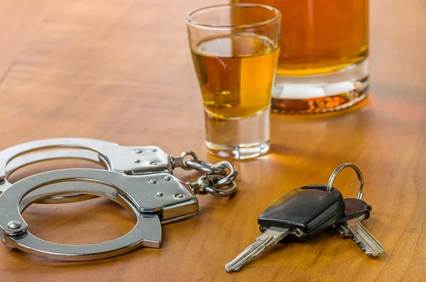 Shot glas met autosleutels en handboeien Rechtenvrije Stockfoto's