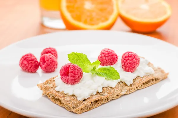 Crispbread with cream cheese and raspberries on a breakfast table — Stock Photo, Image
