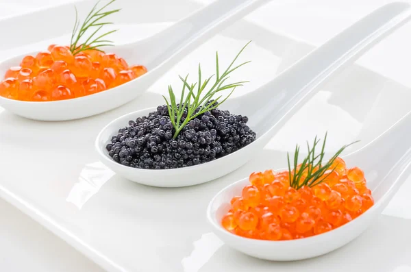 Caviar vermelho e preto em colheres de porcelana — Fotografia de Stock
